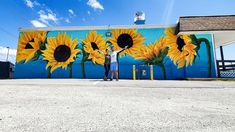 a man standing in front of a painted mural with sunflowers on it's side