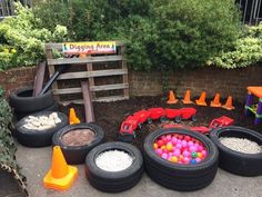 there are many toy cars and toys in the dirt near some tires on the ground