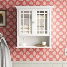 a bathroom with red and white wallpaper, cabinets and towels on the counter top