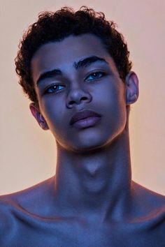 a young man with blue eyes and curly hair is looking at the camera while wearing no shirt