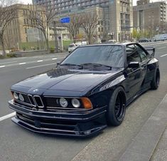 a black bmw is parked on the side of the road