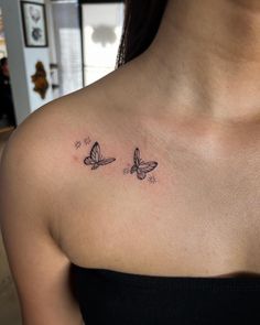 a woman's chest with two small butterflies on the left side of her shoulder