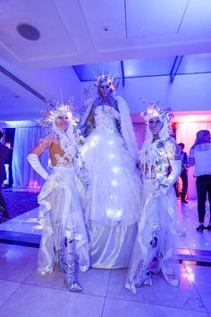 three women dressed up in costumes standing next to each other on a dancefloor