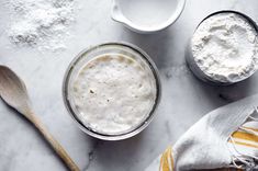 two bowls and spoons on a table with flour