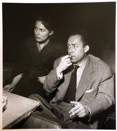 an old black and white photo of two people sitting at a table in the dark