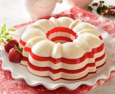 a red and white bundt cake on a plate with strawberries next to it