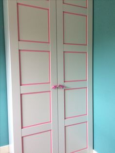 two white doors with pink trim on them in the corner of a blue walled room