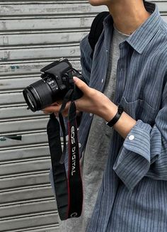 a man is holding a camera in his right hand and looking at the other side