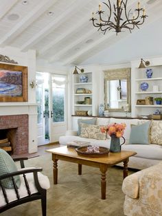 a living room filled with furniture and a fire place under a chandelier in front of a fireplace