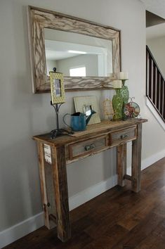 a wooden table sitting under a mirror on top of a hard wood floor