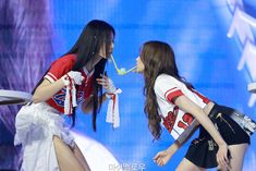 two young women are performing on stage with one holding a toothbrush in her mouth