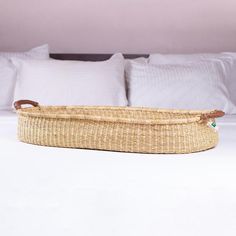 a wicker basket sitting on top of a bed with white sheets and pillows in the background