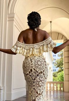 a woman in a white crochet dress walking down a hallway