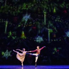 two people are performing on stage in front of a christmas tree and snowflakes