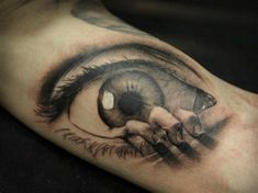 a close up of a person's hand with an eye tattoo on their arm