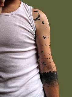 a man wearing a white tank top with birds on his arm