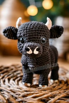 a small crocheted black cow standing on top of a wicker basket