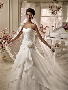 a woman in a wedding dress standing next to a white piano with flowers on it