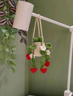 a potted plant hanging from the side of a white shelf next to a lamp