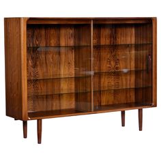 a wooden bookcase with glass doors on the front and bottom shelves, against a white background