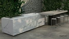 an outdoor kitchen with marble counter tops and barstools in front of a stone wall