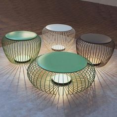 four different colored tables sitting on top of a wooden floor next to each other and one is lit up