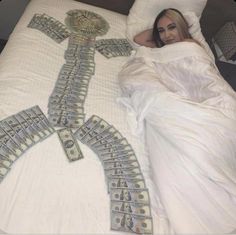 a woman is laying in bed with money on her stomach and the sheets are white