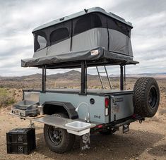 an off - road vehicle with a tent on the back in the middle of nowhere