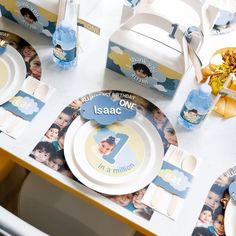 a table topped with plates and cups filled with baby's first birthday pictures on it