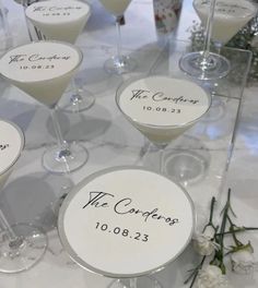 there are many wine glasses on the table with names and date written on them for guests to drink