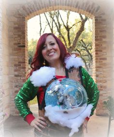 a woman in green and red holding a snow globe