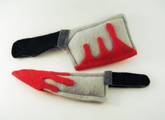 two red and gray hand mittens on white surface with black handles, one in the shape of a glove