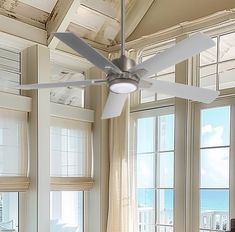 a ceiling fan in a living room with large windows