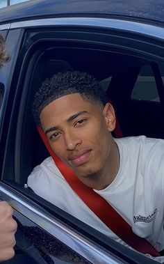 two people sitting in the back seat of a car, one is holding his head out the window