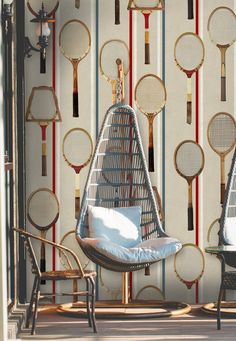 tennis rackets are hanging on the wall behind a chair with a cushion in front of it