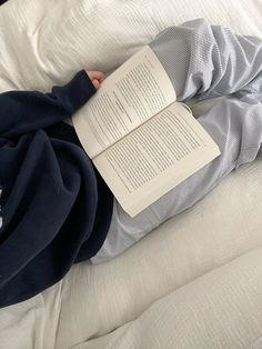 a person laying on top of a bed with an open book