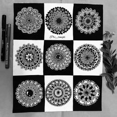 some black and white pictures on a table with markers, pens and paper flowers in the middle