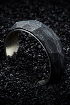 a black and silver ring sitting on top of gravel