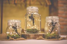 three mason jars filled with fairy lights and figurines on top of a table