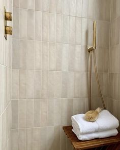 a white towel is sitting on a wooden shelf next to a shower head and hand rail