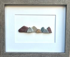 three rocks are arranged in a row on a white background, framed in a wooden frame