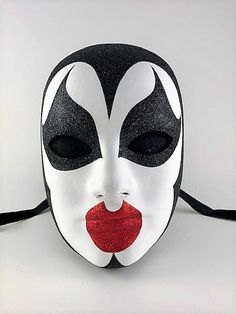 This handcrafted, full face, Venetian volto mask is decorated in shimmering black glitter and red glittered lips, with a pale white painted face, inspiring a glitzy vampire or glitzy demon.  The mask is handmade from paper mache and measures approximately 9" high, 6 ½" wide and 3 ½" deep. The mask has traditional black ribbon ties for a comfortable fit.  All masks are handmade in Venice, Italy. No two masks are ever identical. Colors and patterns may vary slightly on each mask. Volto Mask, Pale White, Costume Masks, Painted Face, Ribbon Tie, Red Glitter, Black Ribbon, Full Face, Black Glitter