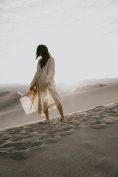 a woman is walking in the sand dunes