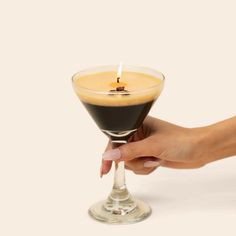 a person holding a drink in a glass with a candle on the top and bottom