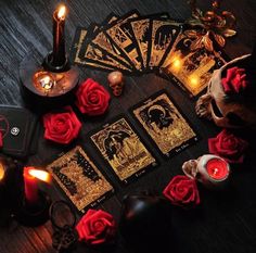 a table topped with cards and candles on top of a wooden table covered in red roses