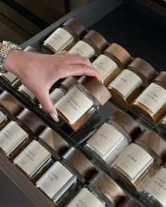 a woman's hand reaching for spices in glass containers