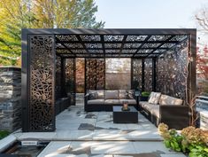 an outdoor living area with couches, tables and pergolated screens on the walls