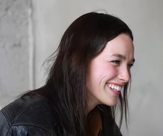 a woman smiling and wearing a black leather jacket