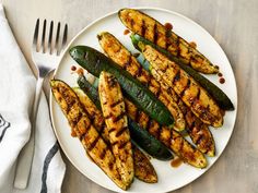 grilled zucchini and green beans on a white plate with silverware next to it