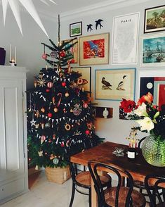 a decorated christmas tree in the corner of a dining room with pictures on the wall